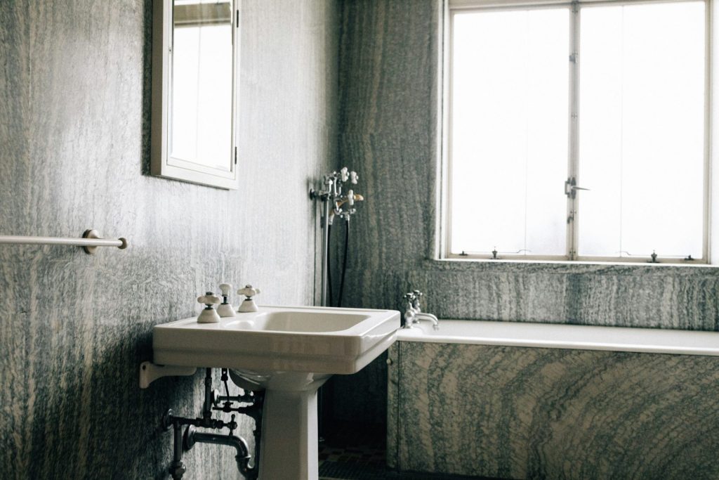 A vintage bathroom with a pedestal sink and bathtub.