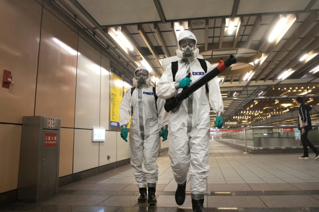 Workers in hazmat suits disinfect a subway station.